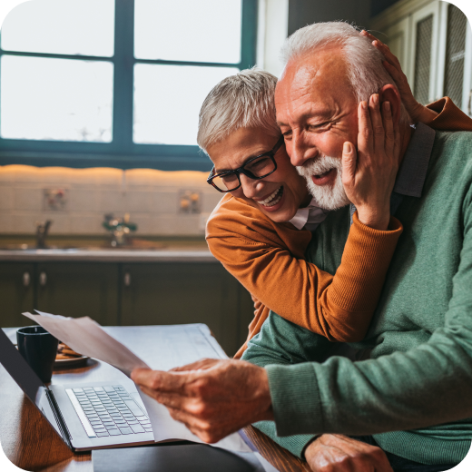 Happy couple reviewing financial documents together at a kitchen table