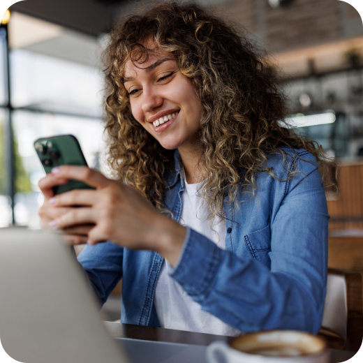 Smiling woman using a smartphone and laptop, representing customer engagement with digital banking