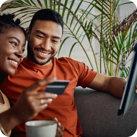 Smiling couple reviewing financial documents on a laptop, illustrating financial wellness